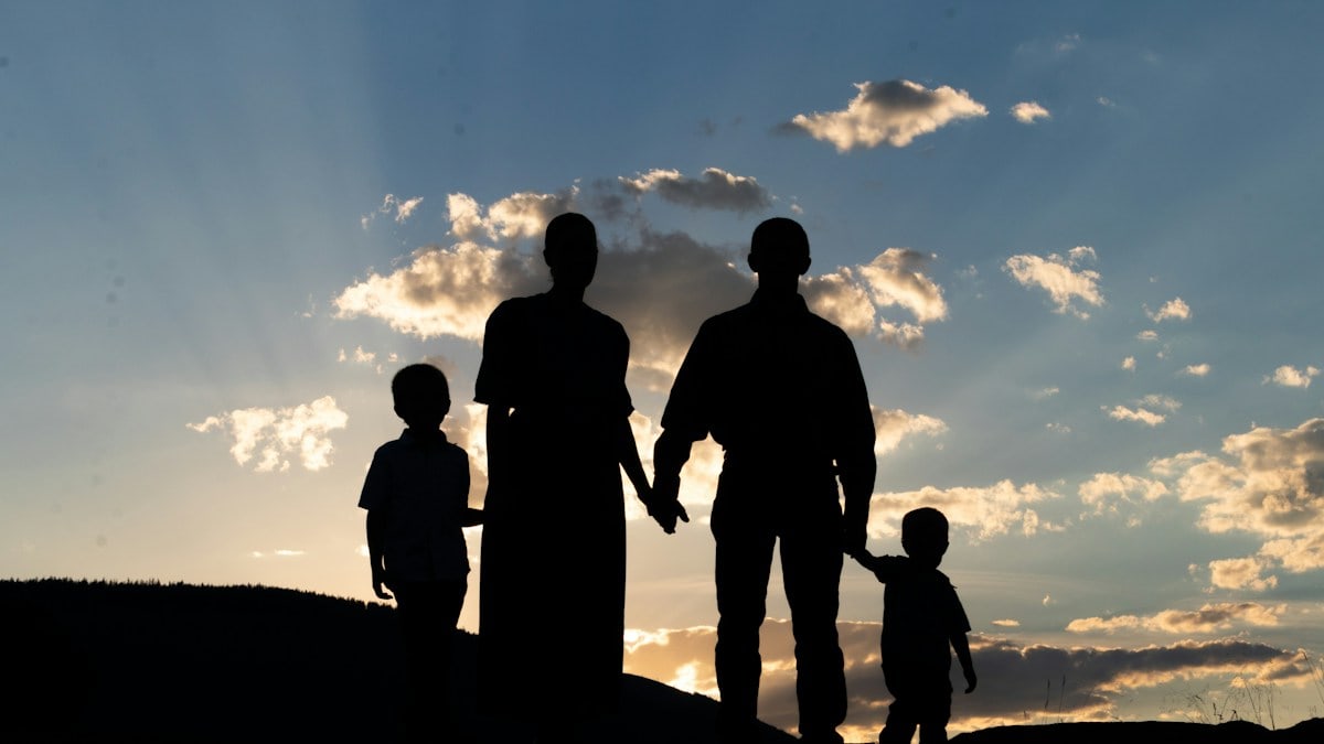 a group of people standing on a hill looking at the sunset